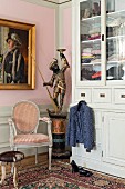 Antique statue, gilt-framed painting and wardrobe in corner of bedroom