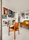 Sofa and gallery of photos in cosy reading corner behind glass desk and armchair