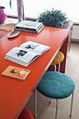 Mit Filz bezogene Hocker unter einem orangefarbenen Tisch