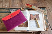 Knitted wool pencil case in red and purple on schoolbook on vintage school desk