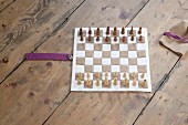 Hand-sewn boiled-wool chessboard and wooden chess pieces on rustic wooden floor