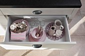 Pink crockery in an open drawer