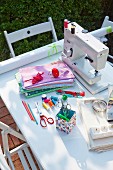 A sewing machine and various sewing utensils on a table outdoors