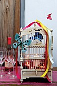 Vintage birdcage decorated with butterfly ornaments, colourful ribbons and lit candles