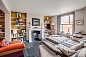 Upholstered furniture and fitted bookcases flanking open fireplace in comfortable living area