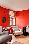Comfortable antique reading chair and modern standard lamp in corner of room with red-painted walls