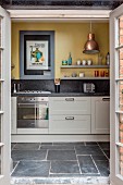 Blick auf helle Küchenzeile mit Granitarbeitsplatte und gelber Wandfarbe
