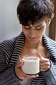 A hand-knitted cup sleeve made of cotton yarn