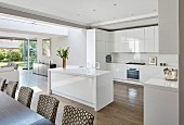 Glossy kitchen cupboards and island counter in open-plan interior