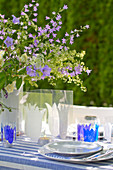 Gedeckter Gartentisch mit Glockenblumen-Deko