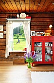 Red dresser next to window with garden view in wooden house