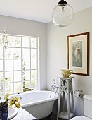 Free-standing bathtub and plant stand in bathroom with large lattice window