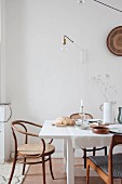 Set white dining table and wooden chairs below light-bulb lamp on wall