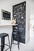 Chalkboard wall covered in drawings next to breakfast bar and bar stools