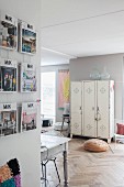 Offener Wohnbereich mit Zeitschriftenständer, Fischgrätparkett und Spind vor grauer Wand