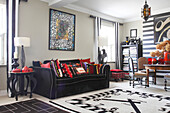 Colourful scatter cushions on black sofa next to clock-face rug