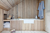 Wood-clad bathtub and walls in bathroom