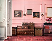 Antique cases and trunks against pink-painted panelled wall