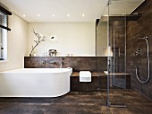 A puristic and elegant designer bathroom with a curved white bath and brown tiles