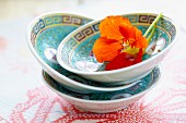 A stack of three oriental bowls decorated with a nasturtium