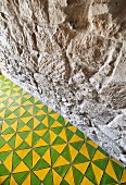 Blick auf Natursteinwand und zweifarbigen Fliesenboden mit geometrischem Muster