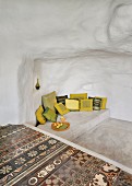 Various cushions on concrete platform next to traditional floor tiles in cave-like interior