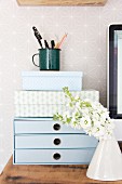Flowers in front of small set of drawers and decorative boxes