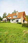 Traditionelles Landhaus mit modernisierter Giebelfassade und grüner Rasenfläche