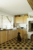 Dog in front of masonry fireplace in fitted kitchen with wooden fronts and hexagonal floor tiles