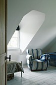 Comfortable blue-striped armchair next to dormer window