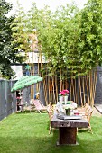 Sommerlicher Innenhof Garten mit langem Holztisch und Bambus