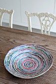 Colourful hand-crafted paper dish on wooden table