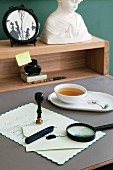 A Biedermeier desk with a letter and seal, an elegant teacup and a framed silhouette