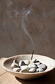 Heart-shaped pebbles and smoking joss stick in wooden dish