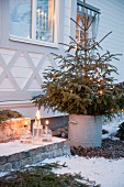 Fir tree in metal bucket and festive lanterns outside Swedish house