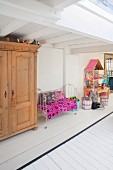 Little girl, dolls' house, vintage bed and wooden cupboard in play area