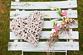White grape hyacinths with heart-shaped pendants next to wicker heart on vintage folding chair