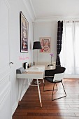 Schreibtisch mit schwarz-weißem Armlehnstuhl vor Fenster