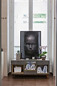 Towels in modern bathroom cabinet with portrait of woman on top in front of French windows