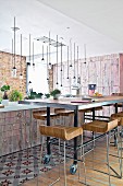 Designer bar stools at long dining table on castors in front of island counter