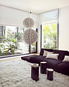 Black sofa and white rug in living room with glass wall