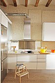 White kitchen counter with extractor hood in high-ceilinged, loft-style interior