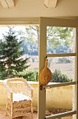 Raffia fan hung on open balcony door with view of landscape