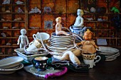 Antique dolls and crockery in front of display case