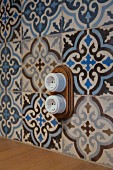 Vintage-style electrical sockets mounted on ornamental, floral wall tiles