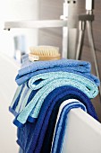 Towels in shades of blue hanging over edge of bathtub