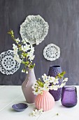 Flowering branches in vases with structured surfaces in various shades of pink and purple