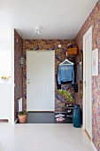 Front door and brightly patterned wallpaper in foyer