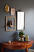 Shoes in frame on wall and old mirror above semi-circular table