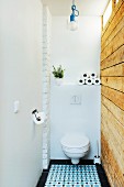 Toilet with rustic, reclaimed board wall and ornate floor tiles